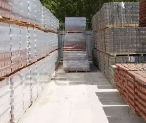 Caracterização de Materiais 3 Pilhas de blocos e tijolos organizados em um pátio para análise de materiais.
