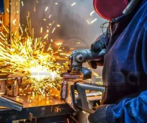 Caracterização de Materiais 4 Soldador trabalhando com metal, gerando faíscas no processo de soldagem.