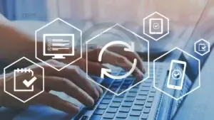 Mãos em um notebook, com ícones hexagonais de atualização e dispositivos ao redor.