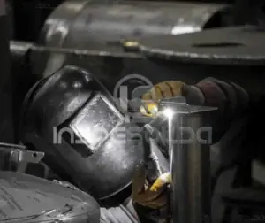 Detalhe de processo de soldagem em ambiente industrial com ênfase nos componentes metálicos.