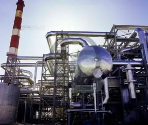 Estrutura industrial com vasos de pressão e tubulações em ambiente fabril.
