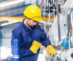 Técnico realiza supervisão e manutenção preventiva em ambiente industrial.
