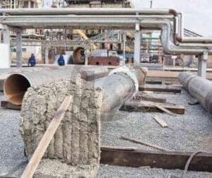 Tubulações em planta industrial, com um trecho envolto em manta térmica em primeiro plano.