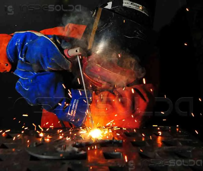 Soldador operando processo com eletrodo revestido em ambiente industrial.
