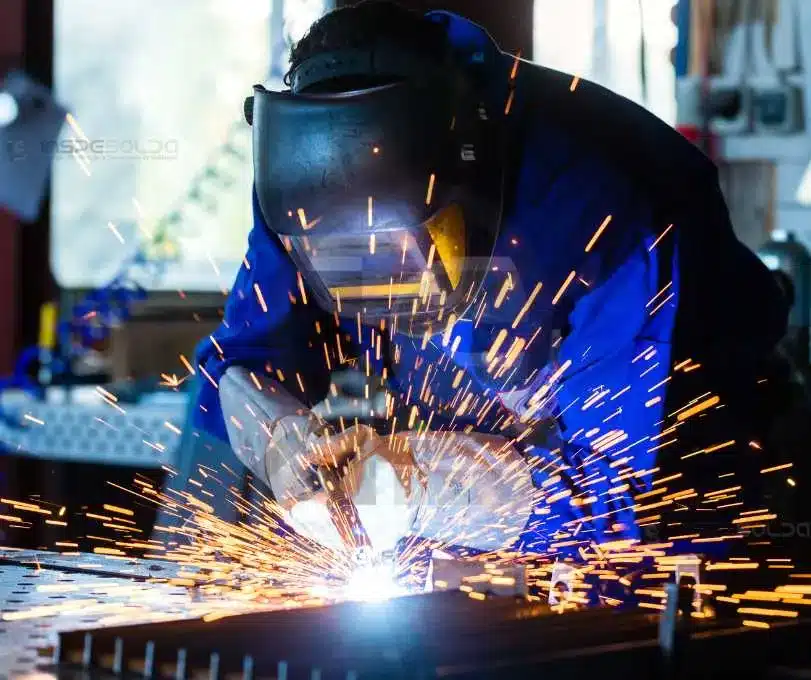 Soldador em treinamento prático, executando execução com faíscas intensas.