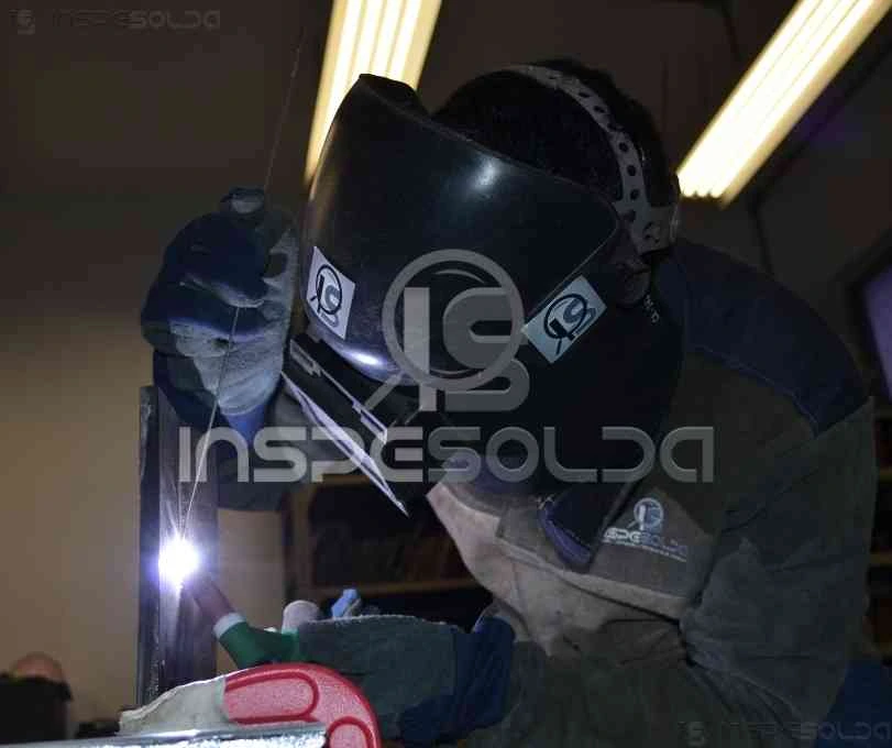 Soldador em ação, utilizando máscara de proteção enquanto realiza um cordão de solda com precisão.