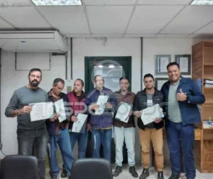Equipe de soldadores reunida, segurando certificados de qualificação, celebrando uma conquista profissional importante.