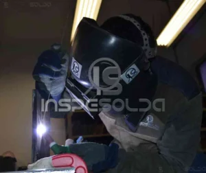Soldador em ação com máscara de proteção, em ambiente controlado, simbolizando a união entre conhecimento técnico, coragem e comprometimento no processo de soldagem.